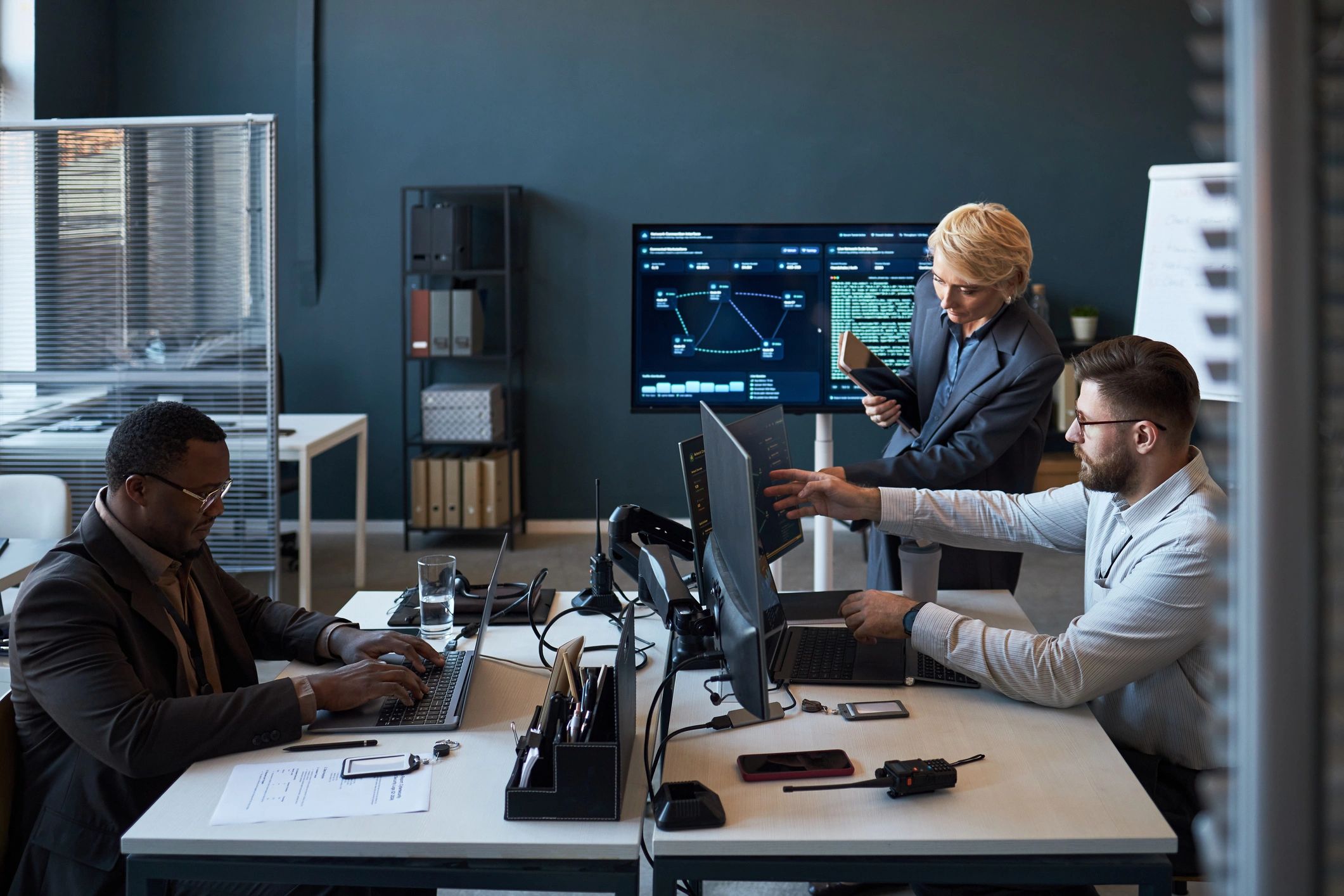 Business team collaborating around cybersecurity and operations dashboards